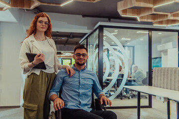 Young business colleagues, collaborative business colleagues, including a person in a wheelchair, walk past a modern glass office corridor, illustrating diversity, teamwork and empowerment in the