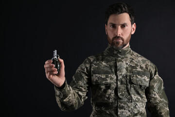 Soldier holding hand grenade on black background. Military service
