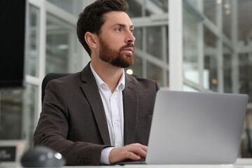 Fototapeta premium Man working on laptop at white desk in office