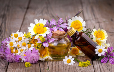 Essential oil in glass bottle with fresh chamomile flowers and variete herbal, beauty treatment.