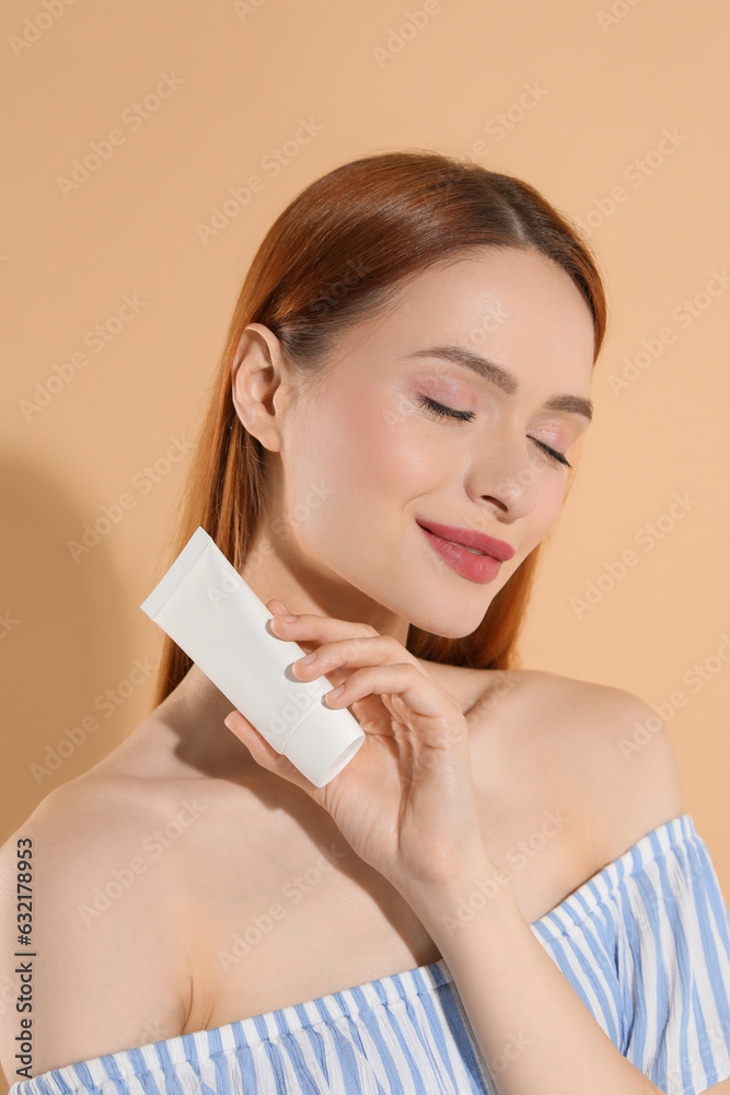 Canvas Prints Beautiful young woman holding sun protection cream on beige background