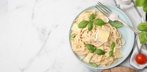 Tasty pasta with brie cheese served on white marble table, flat lay. Banner design with space for text