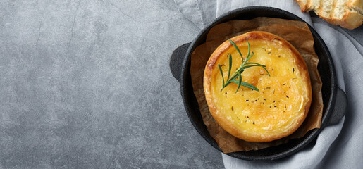 Tasty baked brie cheese served on grey table, flat lay. Banner design with space for text
