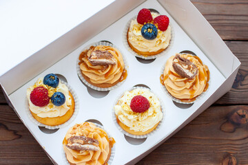Assorted cupcakes in gift box with fresh strawberries, peanut butter, slated caramel, chocolate, raspberry, strawberry and blueberry
