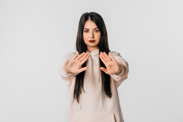 Stop it. Young woman making stop sign with hands, saying no, looking at camera, stands over white...