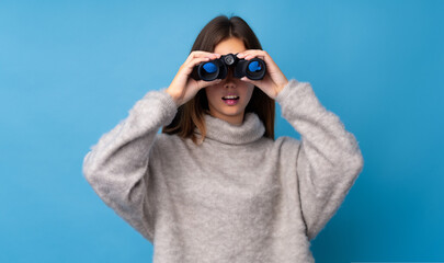Teenager girl with sweater looking through binoculars