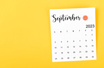 The September 2023 and wooden push pin on yellow background.