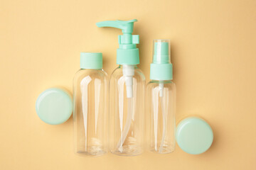Empty travel cosmetic bottles on beige background. Minimalist bodycare beauty products for vacation or journey. Top view. Copyspace.