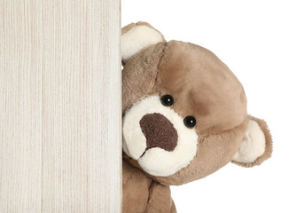Cute teddy bear peeking out of wooden board on white background