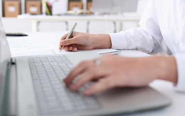 Businesswoman in the office holds her hand on the laptop makes financial analysis and calculation of expenses. Incomes of the enterprise forms a report on work done for reporting period.