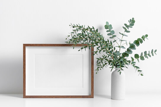 Wooden frame mockup in white interior with fresh eucalyptus plant