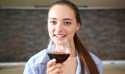 Young beautiful attractive girl drinks wine in the kitchen from a glass at breakfast time, spends...