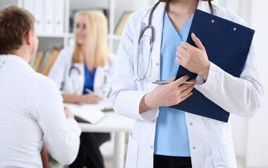 Female medicine doctor hand holding silver pen looking in clipboard pad closeup. Ward round patient visit check 911 medical calculation and statistics concept. Physician ready to examine patient - obrazy, fototapety, plakaty