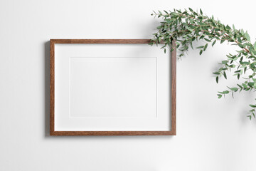 Landscape art frame mockup on white wall with fresh eucalyptus. Blank mock up with copy space for...