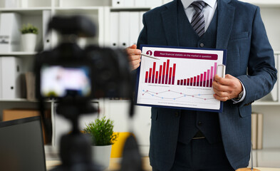 Male in suit and tie show stats graph pad making promo videoblog or photo session in office...