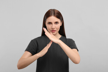Woman showing time out gesture on grey background