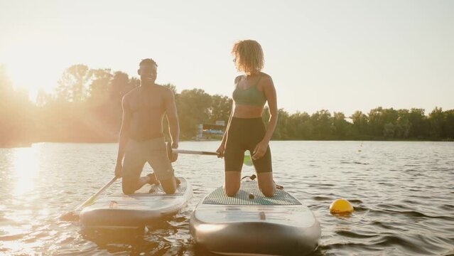 Couple kneeling on sup boards and giving high five