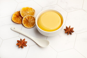 Crema de vainilla dentro de un cuenco blanco junto a una cuchara sobre un fondo de mármol. Vista superior y de cerca. Copy space