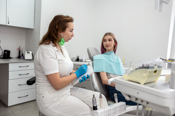 female doctor is client during a consultation with girl patient in dental clinic.