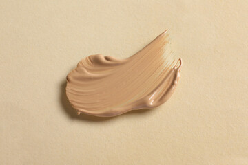 Swatch of skin foundation on beige background, top view