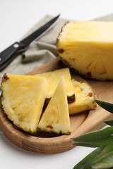 Slices of ripe juicy pineapple and knife on white table, closeup