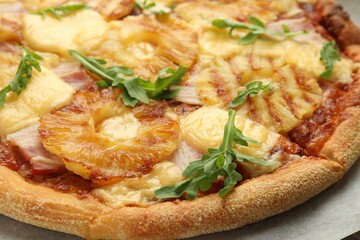 Delicious pineapple pizza with arugula on table, closeup