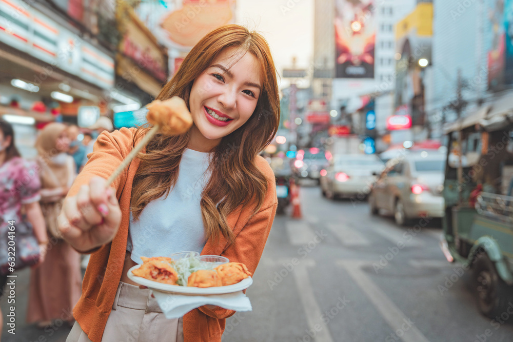 Wall mural happy young tourist asian woman enjoy and fun traditional asian street food at bangkok chinatown, fe