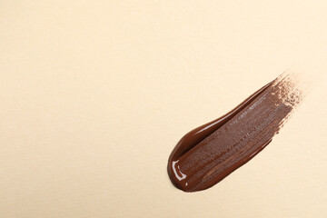 Smear of skin foundation on beige background, top view. Space for text