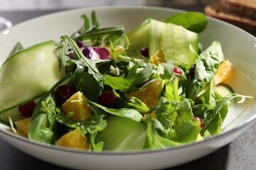 Delicious salad with cucumber and orange slices in bowl on table, closeup