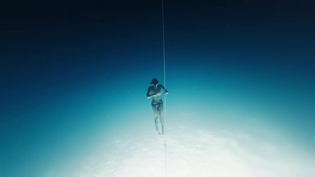 Woman freediver trains along the rope and descends, no fins discipline