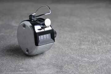Metal, retro mechanical hand counter gray concrete background.
