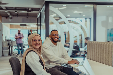 Obraz premium In a modern office setting, an African American businessman and his Muslim colleague, wearing a hijab, engage in collaborative discussions, tackling various business tasks and solving problems