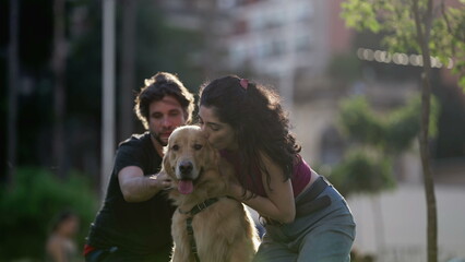 Woman kissing her beautiful Dog outside at park. Couple enjoying weekend activity. Person embracing Golden Retriever pet