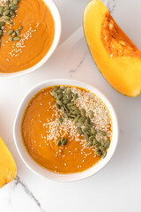 Plates with pumpkin soup puree, pumpkin and sesame seeds. Autumn menu. 
