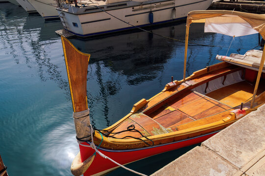 Dghaisa tal-pass with distinctive fore stempost, traditional Maltese water taxi boat without crowd moored on the waterfront of Birgu, Malta.