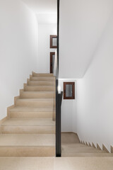 Vertical photo of a clean comfortable staircase with beige walkway black metal railings and white walls in a hotel in a cozy new urban area. Copyspace