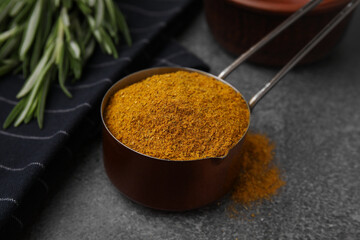 Scoop with curry powder on brown table, closeup
