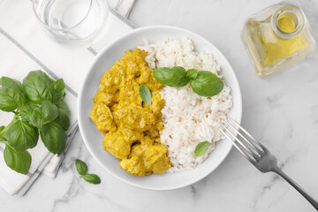 Delicious rice and chicken with curry sauce on white marble table, flat lay