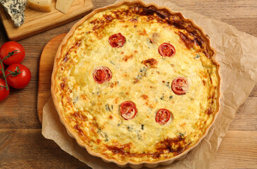 Delicious quiche with cheese and tomatoes on wooden table, top view