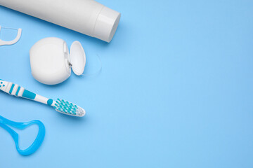 Tongue cleaner and other oral care products on light blue background, flat lay. Space for text