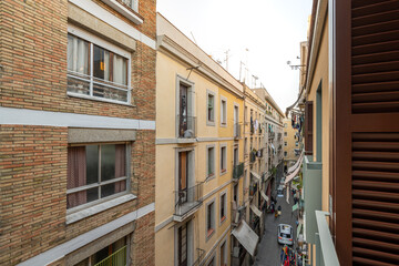 Fototapeta na wymiar View from the balcony to a narrow Barcelona street among modern brick houses with large windows. The concept of modern European architecture