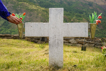 A tomb in the cemetery. A memorial graveyard with a cross. putting flowers on grave in cemetery