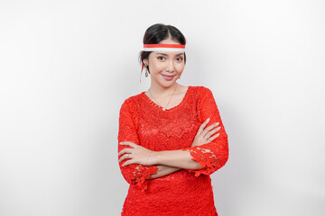 A confident Indonesian woman folding her arms and wearing red kebaya and Indonesia's flag headband...