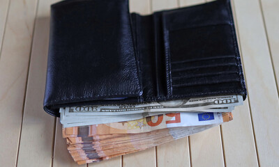 A leather wallet stuffed with euro notes and dollars. Portfel skórzany wypchany banknotami euro i dolarami - obrazy, fototapety, plakaty
