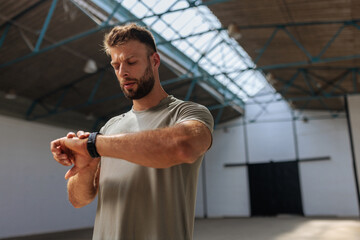 Fit man looking at his watch at the gym