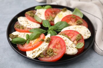 Plate of delicious Caprese salad with pesto sauce on grey table, closeup