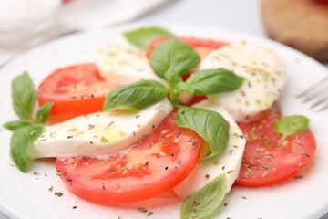 Delicious Caprese salad with herbs on plate, closeup