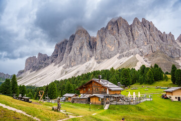 Fototapeta na wymiar Dolomite landscape in Puez Odle Nature Park - view from alpine plateau with wooden houses and green meadows