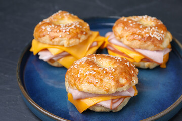 Delicious bagels with ham and cheese on black table, closeup