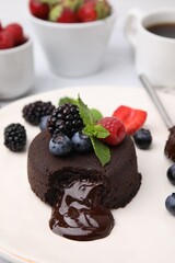 Delicious chocolate fondant, berries and mint on plate, closeup